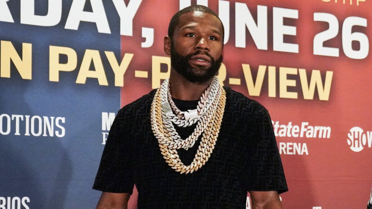 A photo of Floyd Mayweather in a black t-shirt wearing many gold chain necklaces